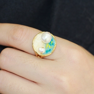Détail d'une bague en émail bleu et blanc de style vintage avec perles naturelles