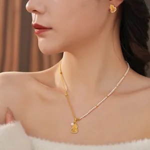 Parure de bijoux gourde en or 18 carats et perles portée par un mannequin