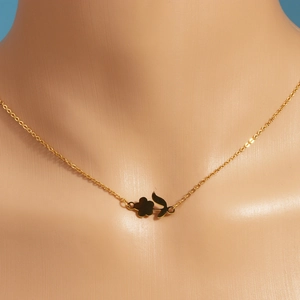 Detailed close-up of a golden rose flower pendant necklace on a neck mannequin