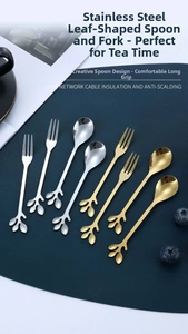 Close-up of gold and silver leaf-shaped dessert spoons on a luxury dark blue mat