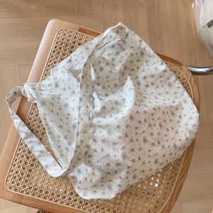 Détail d'un sac cabas en coton à fleurs gris clair sur une chaise en rotin