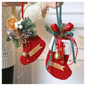 Detail of red knit Christmas stockings with pine cones, cinnamon, and jingle bells