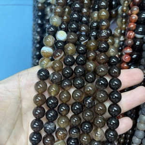 Hand hält polierte Natursteinperlen für DIY-Schmuckherstellung und runde Armbandgestaltung