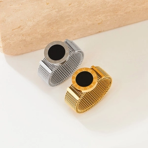 Roman numeral mesh band rings in gold and silver finish on a neutral stone display