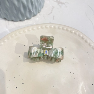 Macro shot of acetic bow hair claw with marble texture and centerpiece rhinestone