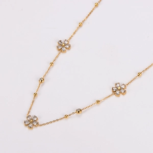Golden stainless steel necklace featuring sparkling crystal flower pendants on a beaded chain