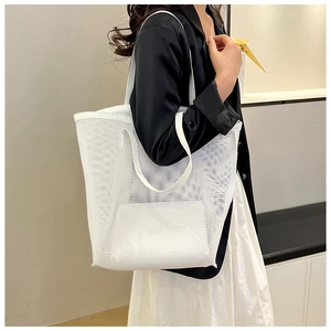 Detailed view of white mesh tote bag with inner pouch worn by a model in a minimalist setting