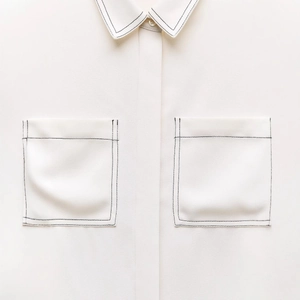White button-up shirt with contrast black stitching and functional double pockets