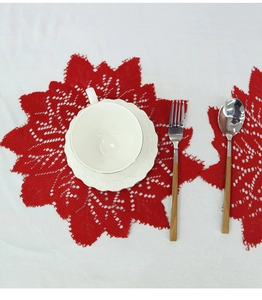 Close-up of red lace coaster featuring an intricate maple leaf pattern and crochet texture