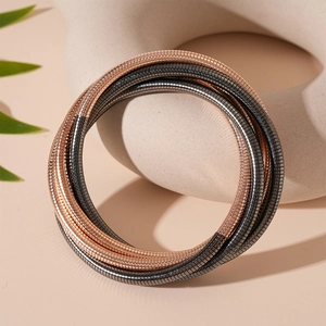 Detail von mehrlagigen Schlangenknochen-Armbändern in Roségold und Gun Black auf Ständer
