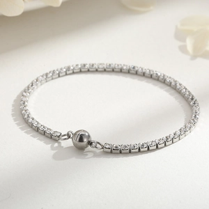 Bracelet tennis en cristal argenté avec fermoir magnétique sphérique sur fond beige