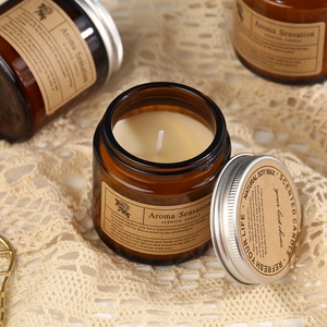 Amber glass scented candle with silver lid on lace cloth, natural soy wax aroma