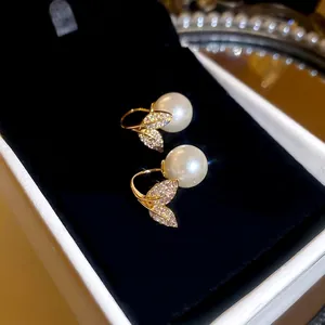 Elegant gold fish tail leaf earrings with pearls and pavé zircons on black velvet
