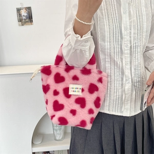 Detail of pink plush tote bag featuring red heart patterns and soft faux fur texture