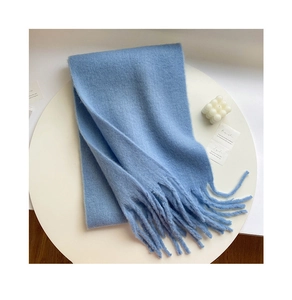 Flat lay of soft light blue scarf with tassels on white table with candle decor