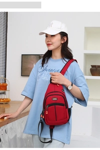 Detail view of red nylon chest bag featuring triple zipper pockets and a side mesh water bottle holder