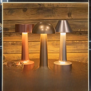 Three minimalist metal table lamps in bronze, gold and silver finishes with warm light