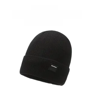 Detailed view of black ribbed knit beanie with a square mountain patch and fold-over cuff