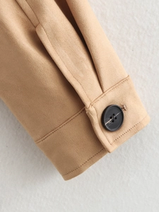 Detailed macro view of warm beige suede jacket cuff featuring a black resin button