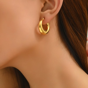 Close-up of chunky gold hoop earrings with a polished finish worn on a model