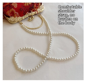 Détail de la bandoulière en perles blanches élégantes sur un sac vintage brodé rouge