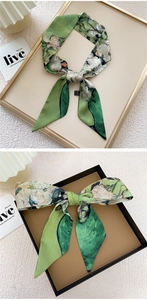 Detail of green floral skinny scarf tied in loops and bows for handbags and hair styling