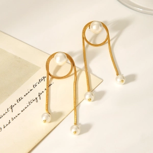 Elegant gold snake chain tassel earrings with white pearls on a minimalist white surface