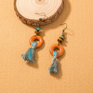 Detail of bohemian long tassel earrings with wooden rings and colorful cotton fringe