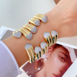 Stack of gold open heart rings featuring micro-pave cubic zirconia on models hand