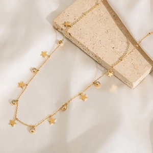 Detail of 18k gold plated stainless steel star necklace with crystal stones on white silk