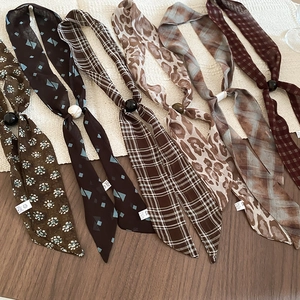 Flat lay view of multiple patterned chiffon neck scarves with central decorative bead ring