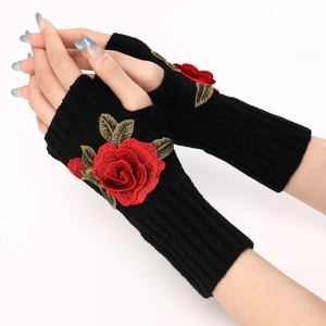 Close-up of black knitted fingerless gloves featuring red 3D rose embroidery and leaves