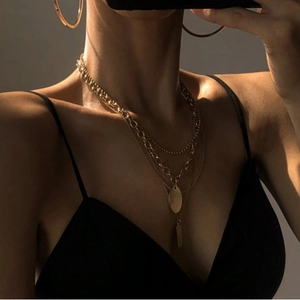 Layered gold titanium steel necklace set with round and square pendants on a model