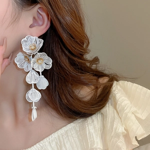 Close-up of white layered flower tassel earrings with intricate petal texture on model