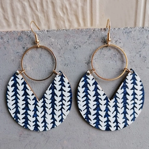Detail of bohemian geometric earrings with blue leaf patterns and golden metal rings