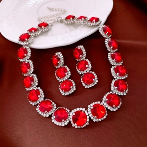 Detail of red gemstone jewelry set with crystals on silver-tone necklace and earrings