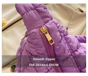 Detail of smooth gold metal zipper on purple quilted nylon puffer shoulder bag