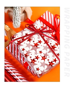 Detailed view of star and striped wrapping paper rolls with festive gift boxes on orange backdrop