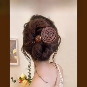 Détail d'une pince à cheveux vintage rose séchée marron avec une perle ambrée sur modèle