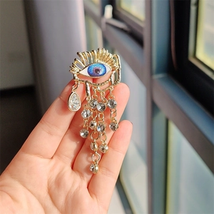 Detailed macro view of a gold eye brooch with blue stones and tassel chains