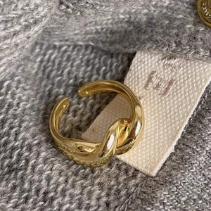 Detailed view of an adjustable gold twisted knot ring on a soft fabric background