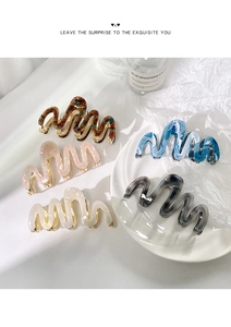 Detail showing wavy acetate hair claws in various colors with metallic teeth