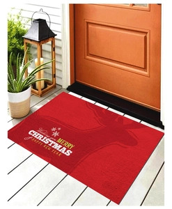 Détail du paillasson de Noël avec silhouette de renne et vœux festifs sur un porche
