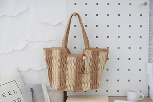 Close-up of brown and beige striped straw tote bag with beaded tassel on a pegboard
