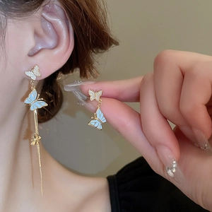 Détail macro de boucles d'oreilles papillon en émail bleu clair avec glands scintillants