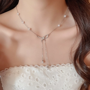 Detail of elegant bow pendant necklace with pearls and rhinestones on model neck