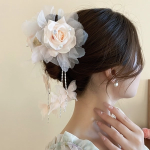 Détail de pince à cheveux fleur rose avec strass, papillon en dentelle et franges