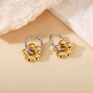 Close-up of two-tone flower earrings in gold and silver finish on white stones