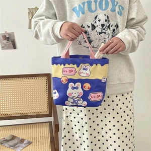 Close-up of model holding blue and yellow canvas tote bag with cute rabbit print