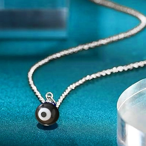 Detailed view of silver stainless steel chain with a spherical evil eye bead pendant